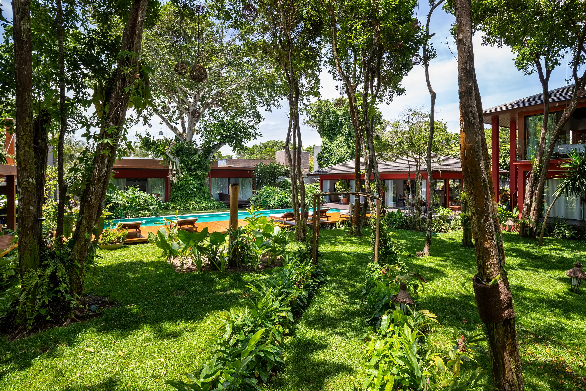 Vista do jardim ao nível do chão, em direção à piscina, às suítes e à casa da piscina